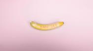 Picture of a banana in a condom on a pink background
